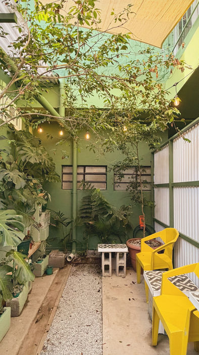 Private garden patio at Studio 01 with yellow chairs, tropical plants and a peaceful outdoor atmosphere.