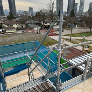 Top view of three-level stair tower platform with short walkway bridging the gap above the roof, installed by IBEK Scaffolding Ltd at Brentwood Secondary School, Burnaby, BC.