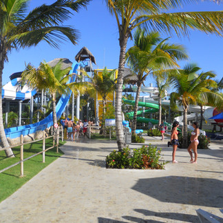 Splash Water Park;Splash Water Park near Royalton Punta Cana; big blue and white water slide and a blue water slide surrounded by many palm trees; a few people are standing and talking