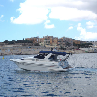 old buildings in the background; a white motor boat on the water; a few clouds on the sky