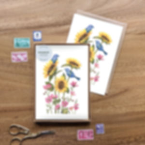 A notecard set featuring a watercolor illustration of bluebirds perched on sunflowers and pink flowers.
