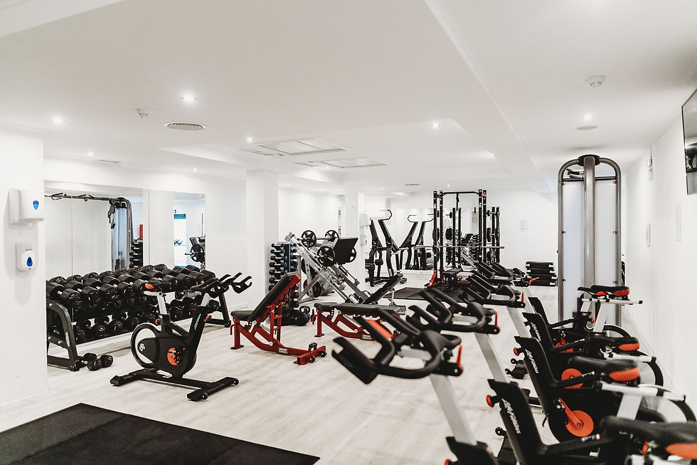 A gym area where machines, barbell, dumbells are placed.