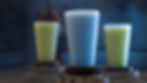 Three glasses with blue and green drinks