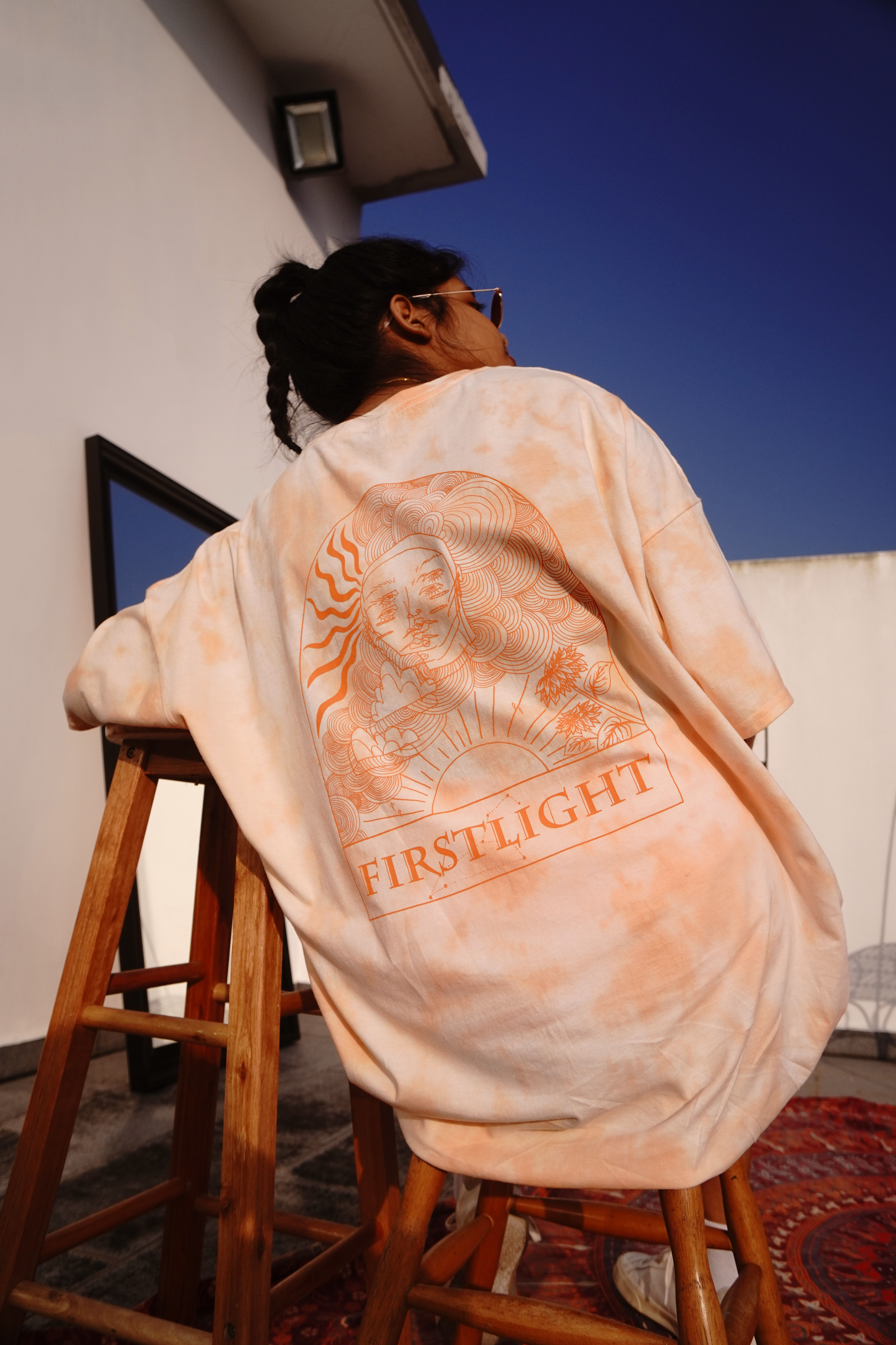 Back view of Firstlight design: Leo constellation, the sun, sunflowers, a face and clouds