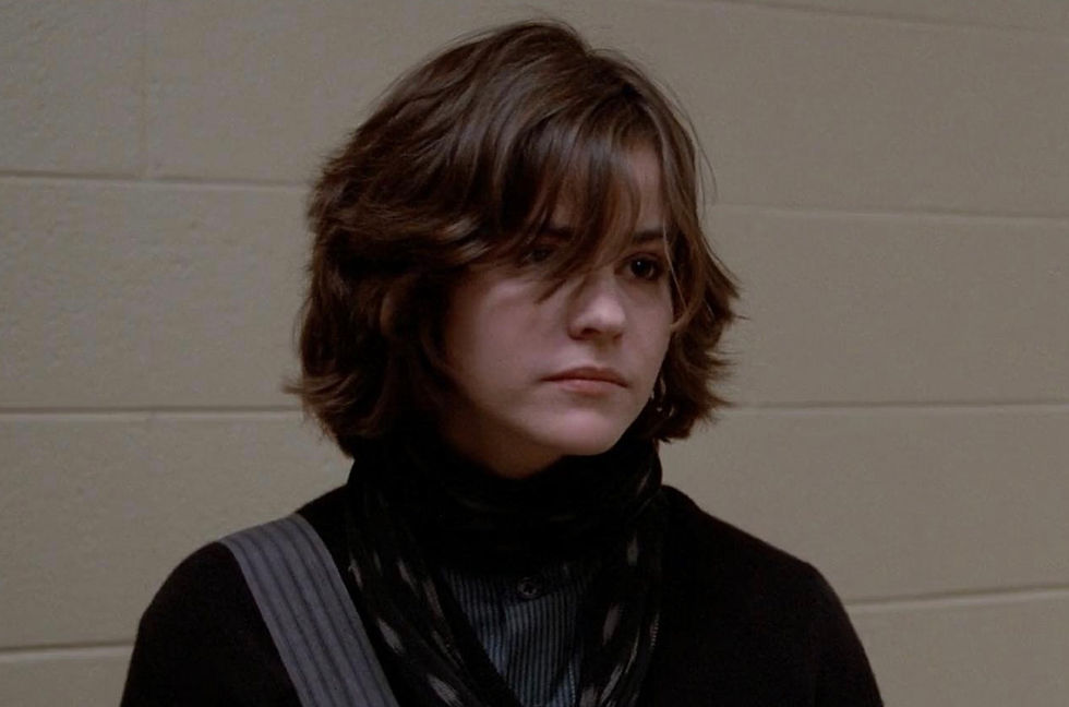 Alyson Reynolds (Ally Sheedy) with her hair covering her eyes, standing against a wall