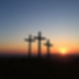 three crosses together on a hillside from a distance with a sunset.jpg