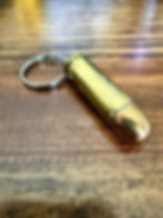 .45 COLT brass bullet keychain made from an authentic once-fired cartridge case on a rustic wood background.