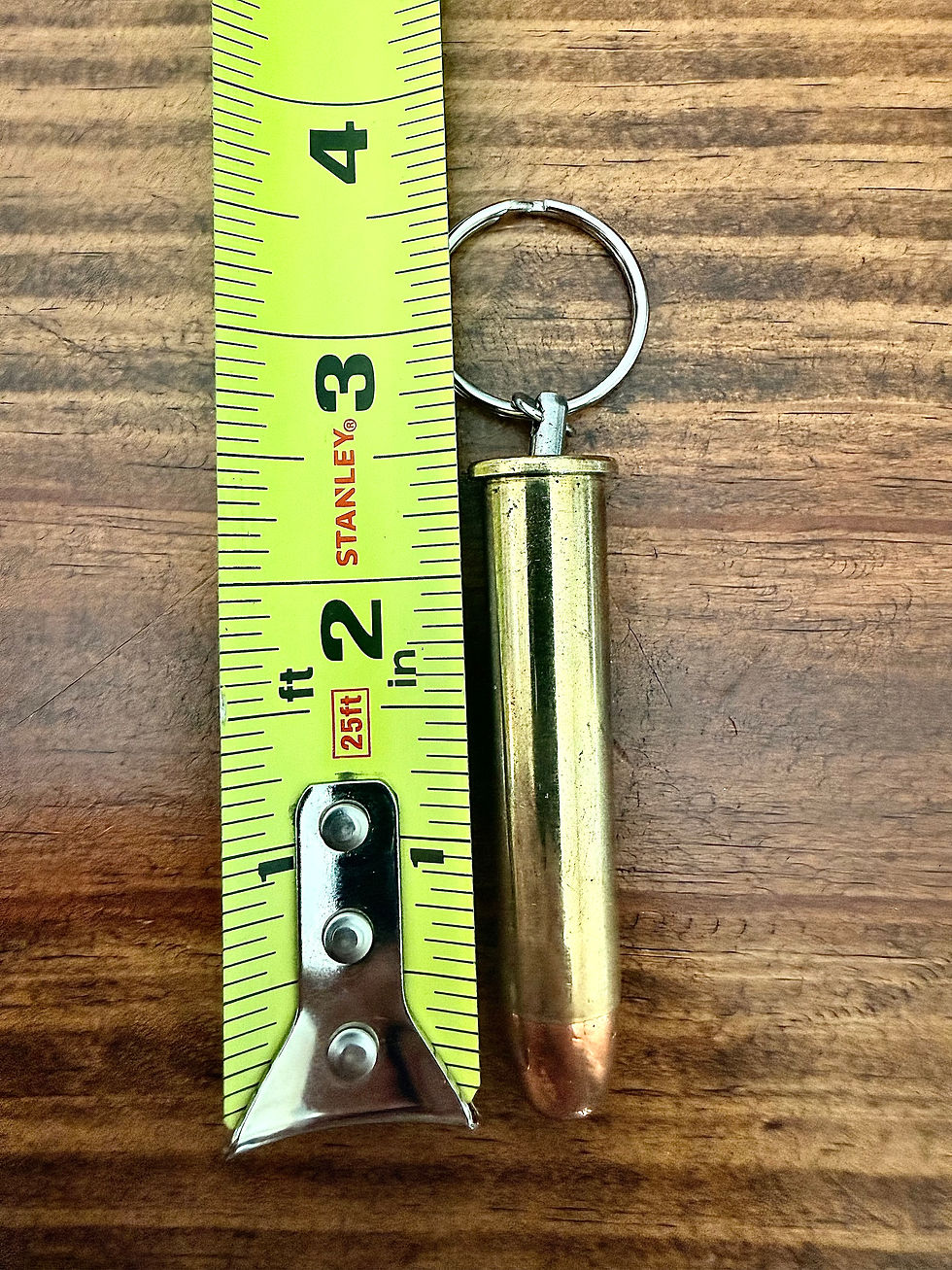 45-70 brass bullet keychain shown beside a tape measure for size reference on a rustic wood background.