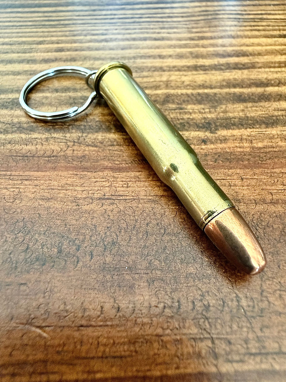 30-30 brass bullet keychain made from an authentic once-fired cartridge case on a rustic wood background.