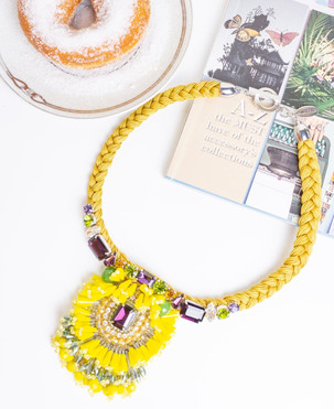 Una collana che ravviva qualsiasi donna la indossi. Un design cangiante e colorato, una corda cerata sui toni del giallo da cui prende vita uno spettacolare susseguirsi di Cristalli e Cristalli Swarovski sui toni del prugna, del verde, dell’arancione e del bianco; per poi confluire in un centrale a forma di fiore con un Cristallo Swarovski rettangolare color prugna al centro e una cascata di petali in cristallo color giallo e bianco. Bijoux ipoallergenici, senza nichel e cadmio.
Questi gioielli sono realizzati con materiali di alta qualità: perle d'acqua dolce, pietre semipreziose, metallo, cristalli e cristalli Swarovski.
In laboratorio viene effettuato un attento controllo qualità; piccole differenze non sono difetti ma garanzia dell'unicità della lavorazione artigianale. La targhetta metallica VANITY HER JEWELS garantisce l'autenticità del prodotto.