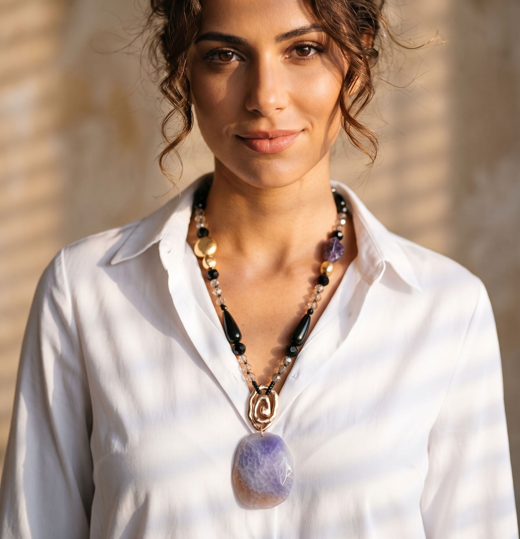 Statement long necklace featuring a large pendant of natural stone with purple shading, gold-tone spiral detailing.