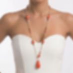 Long necklace with red or turquoise resin beads, a central teardrop pendant, and a gold-plated chain.