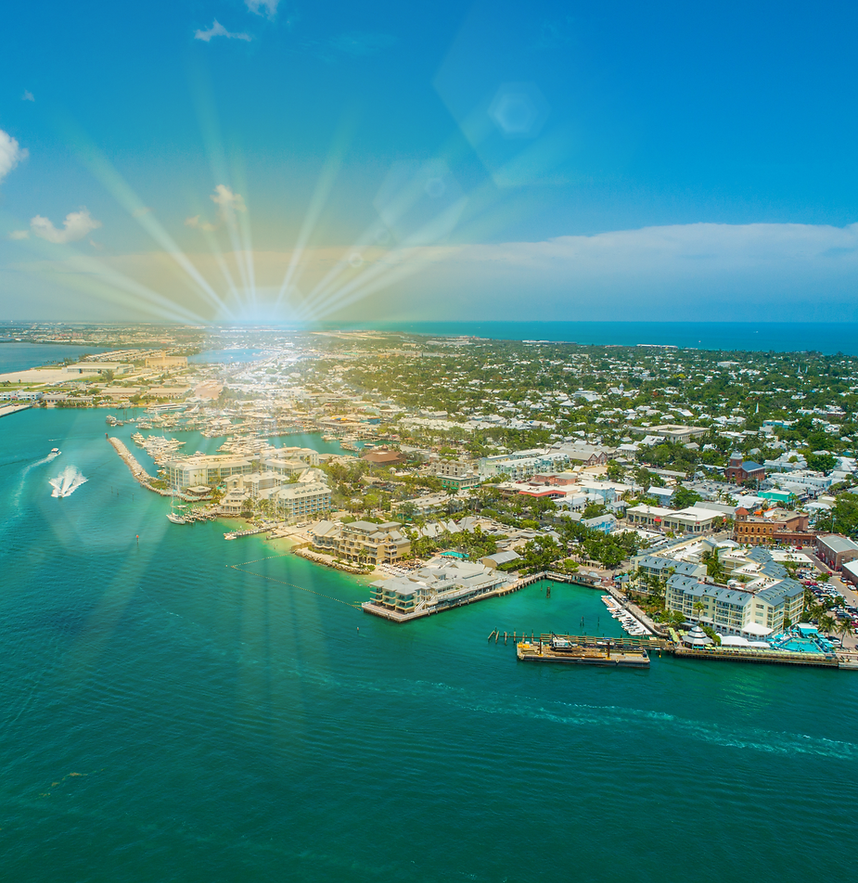 a sunburst gleaming upon an overview image of Key West surounded by water showing the beauty of the location where Key West real estate agents, ShineGroup, have listings