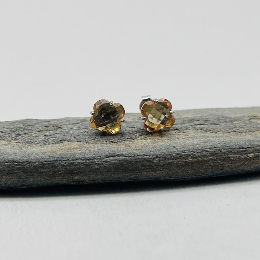 Zultanite Faceted Earrings displayed on dark stone, showing small colour-changing faceted studs.