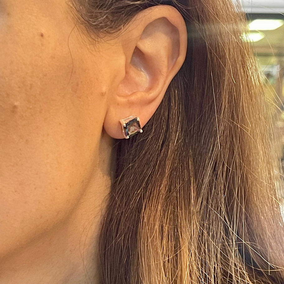 Mystic topaz stud earring worn on the ear, showing its small square gemstone setting.