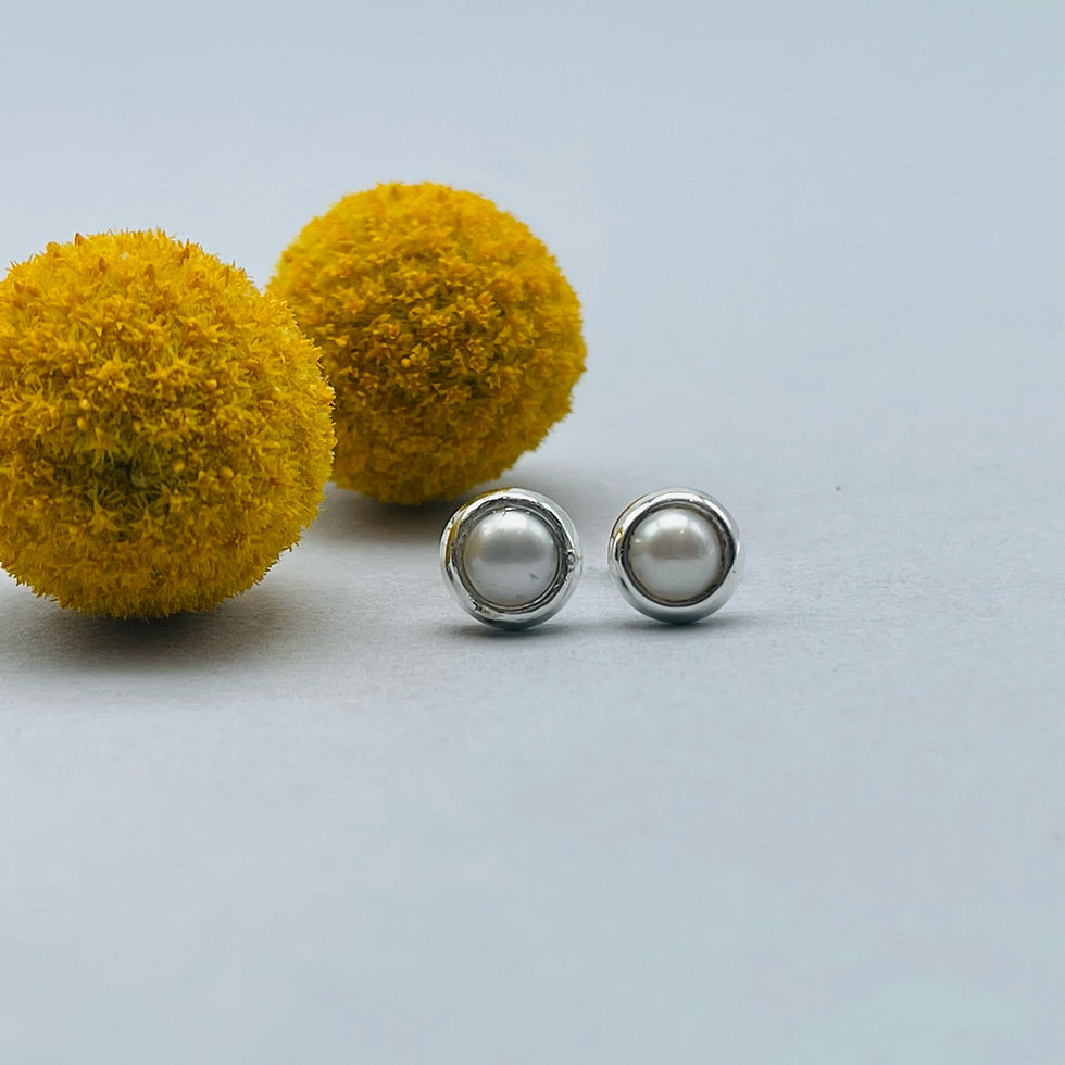 Pearl Stud Earrings displayed beside yellow flowers, showing lustrous pearls set in polished silver.