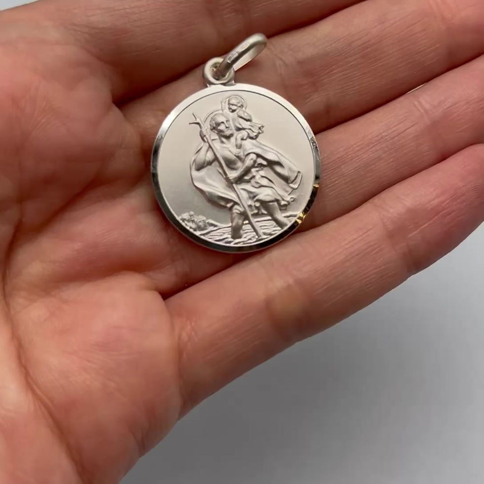 Saint Christopher silver pendant held in a hand, showing the round 24mm size and polished finish.