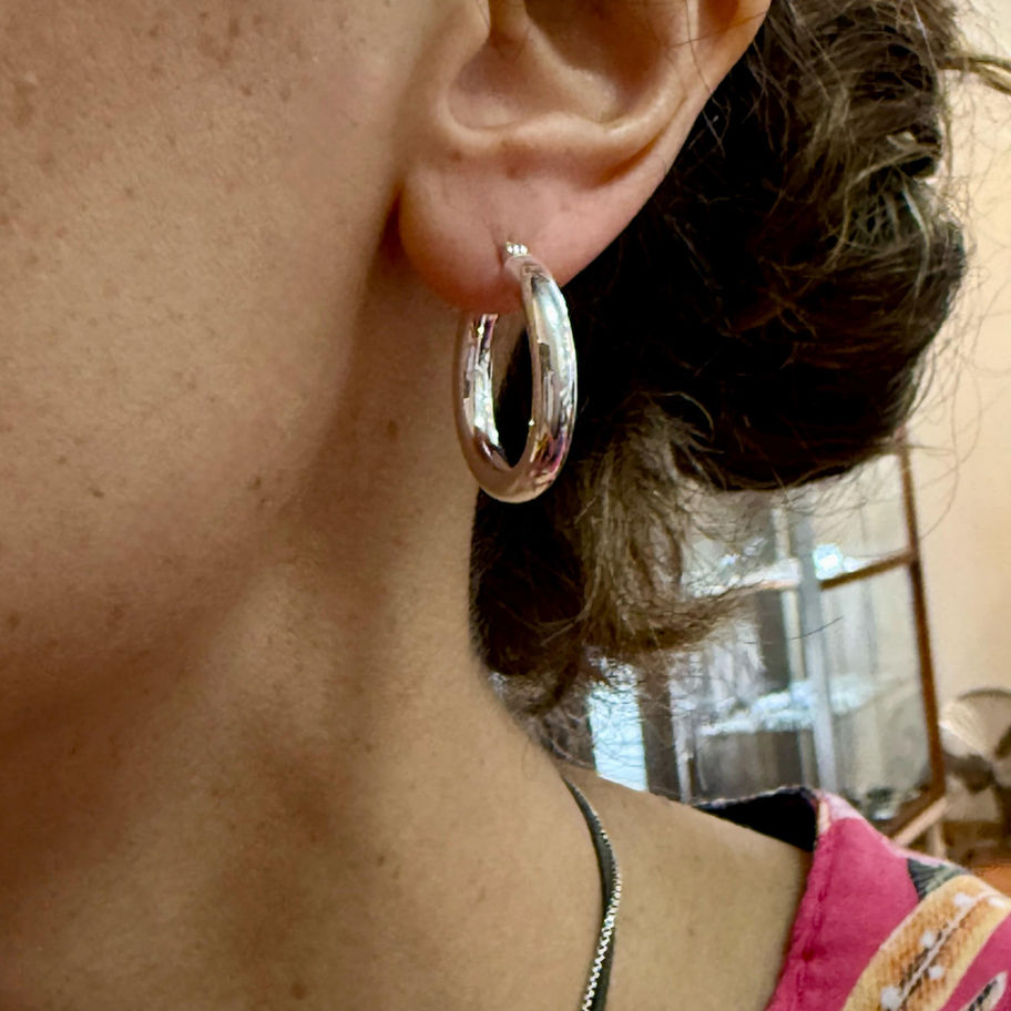 Silver Tube Hoop Earring worn on the ear, showing the rounded polished hoop shape.