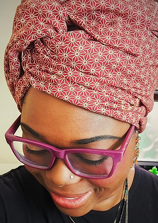 Customer Zehava smiling in a red geometric-print Sprkly head covering and pink glasses
