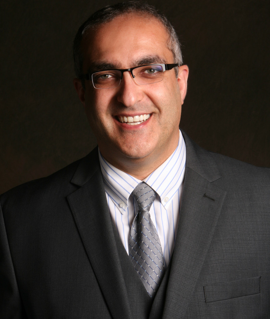 Smiling man in glasses, wearing a suit, professional business portrait.