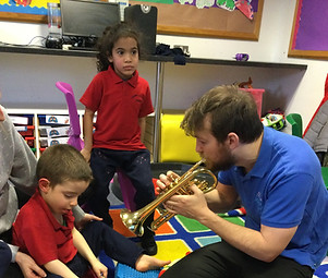 Music therapist playing trumpet to young NI children