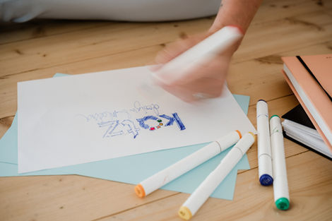 en skrivande eller målande hand som ritar en logga på papper 