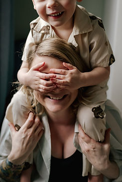 en pojke som sitter på sin mammas axlar täcker för hennes ögon