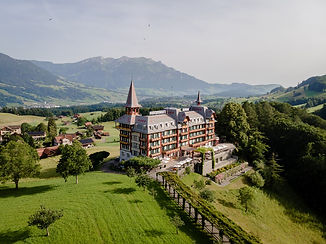 Drohnenaufnahme des Jugendstil-Hotels Paxmontana in Flüeli-Ranft mit Blick auf grüne Hügel, das Sarneraatal und die Zentralschweizer Alpen – perfekte Hochzeitslocation mit Panoramablick, fotografiert von Hochzeitsfotograf Mischa Baettig