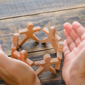business-success-concept-on-wooden-table-top-view-hands-protecting-wooden-figures-of-peopl