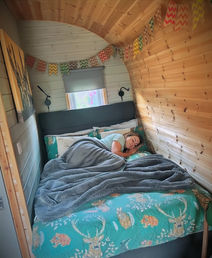 A woman sleeps soundly in a double bed inside a glamping pod at Emlyn's Coppice glamping in Flintshire