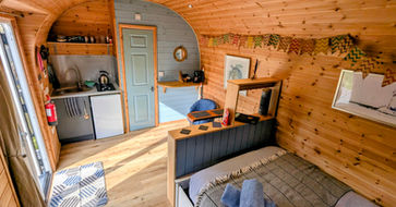A glamping pod interior at Emlyns Coppice in North Wales. Showing a kitchenette, a bathroom door, and a double door glass entry.