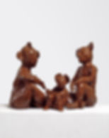 3 gloss-varnished, terracotta clay figures, two larger figures sat on either side of a smaller figure in the middle.
