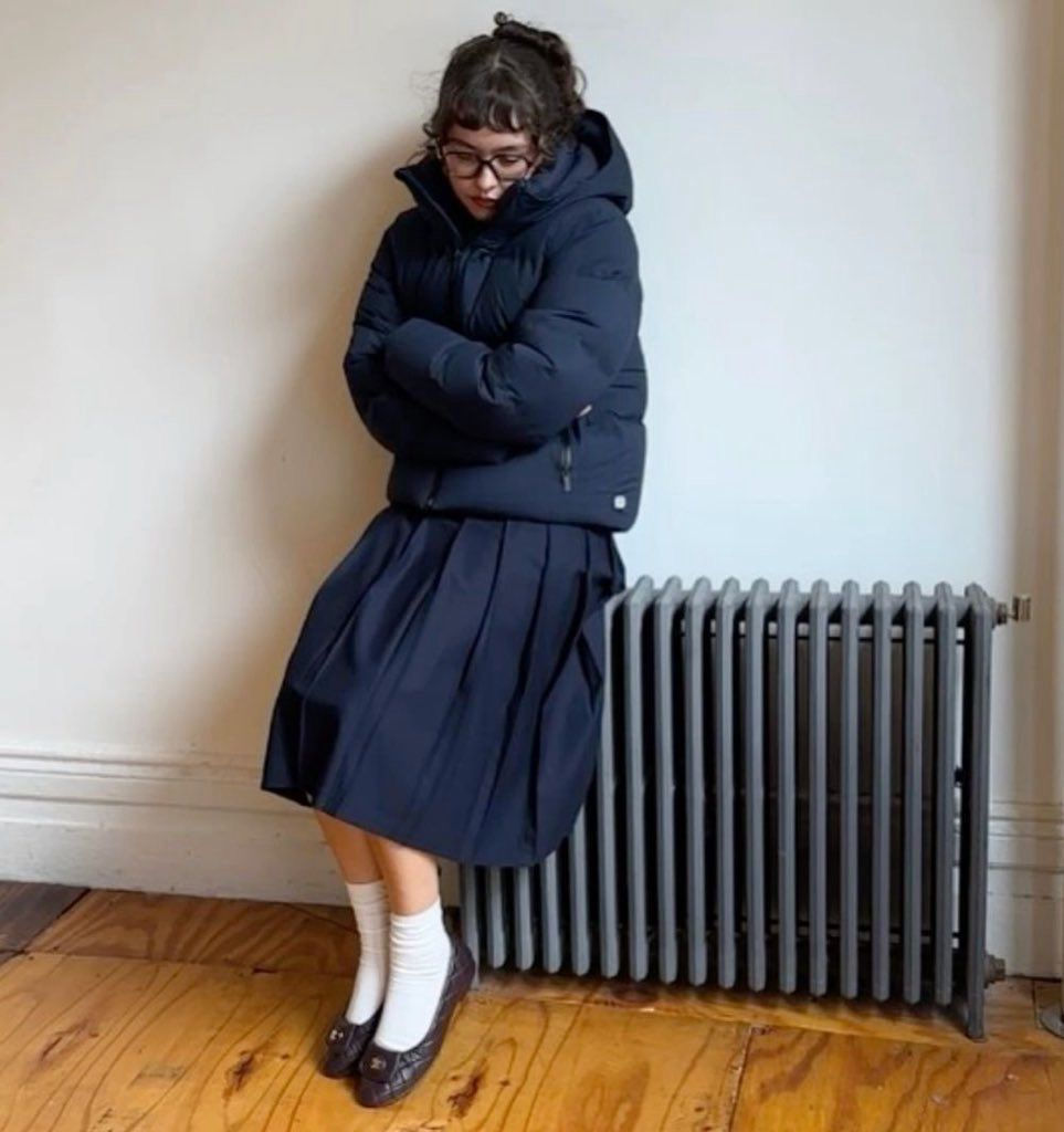 Girl wearing puffer jacket, skirt, ballerinas, socks and glasses- trendy look