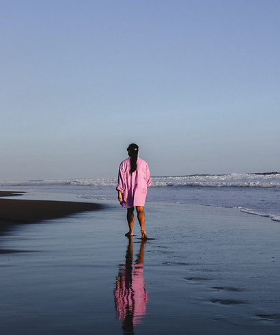 Sonal wearing a pink dress walking away on a beach