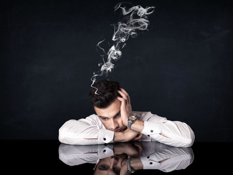 Man in white shirt, head resting on arms, smoke rising from head, reflective surface, black background, contemplative mood.