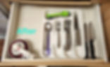 After - Decluttered, organized kitchen drawer with utensils in utensil container and measuring items nested