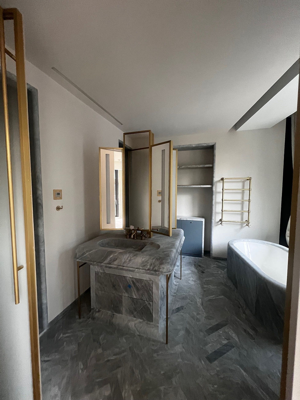 Salle de bain en marbre dans un appartement de luxe rénové à Monaco avec baignoire et meuble vasque haut de gamme.