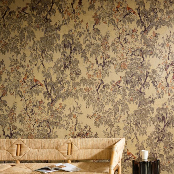 Papier peint Arte motif arbres et oiseaux sur fond doré, ambiance nature élégante avec banquette en rotin – Atelier Marceau Nice