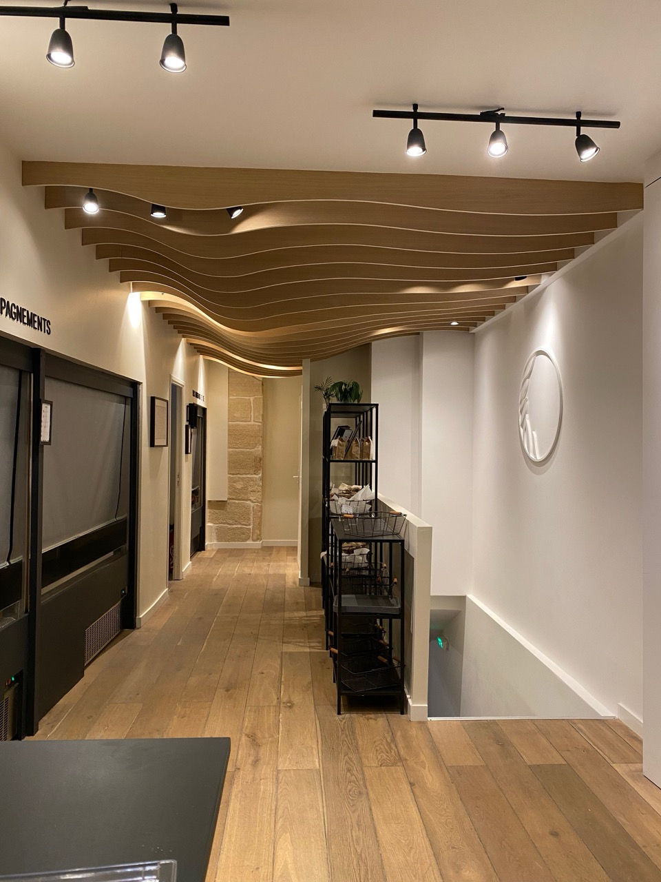 Faux plafond ondulé en bois du restaurant Elkara Paris 4e — lames en vagues et éclairage sur rail