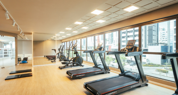 Espaço fitness e academia totalmente equipada com aparelhos modernos de musculação e aeróbicos, espelhos nas paredes e climatização integrada.