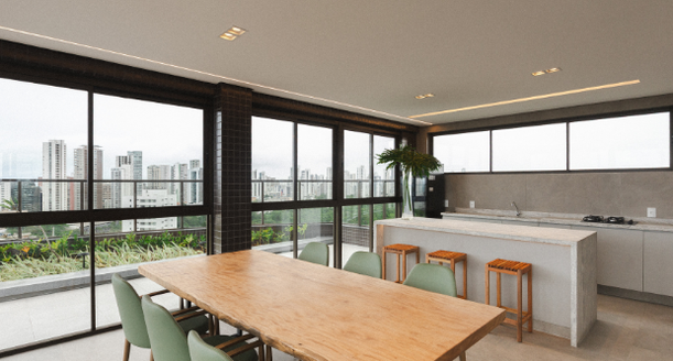 Área interna do lounge gourmet na cobertura, com balcão em mármore, banquetas altas, marcenaria planejada requintada e decoração contemporânea.