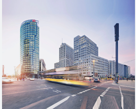 Cityscape at sunset with modern glass skyscraper and busy street. Motion blur of a passing bus, capturing urban energy and movement.