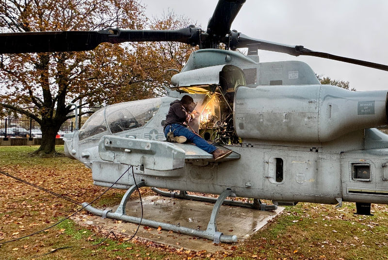 Fabricators help secure the rotor system of an AH-1Z Cobra