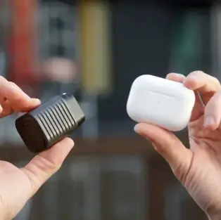 Supertiny 100W GaN charger by Rolling Square held next to AirPods case showing compact size comparison