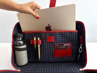 Hand placing a laptop into the ENTE Roomy V2 split case handbag