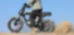 AOTOS Flux X26 Pro eBike ridden on sandy terrain showing off-road capability, moto-style electric bike with dual hydraulic suspension and 100Nm torque