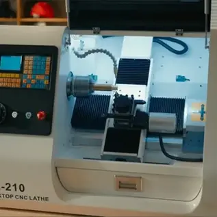 Apanmeker DL 210 CNC Lathe with its front enclosure open, revealing the chuck, tool turret, controller, and internal machining area.