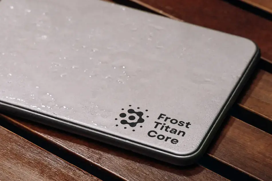 Close-up of the Frost Titan Core titanium ice pack with water droplets and the brand logo printed in one corner
