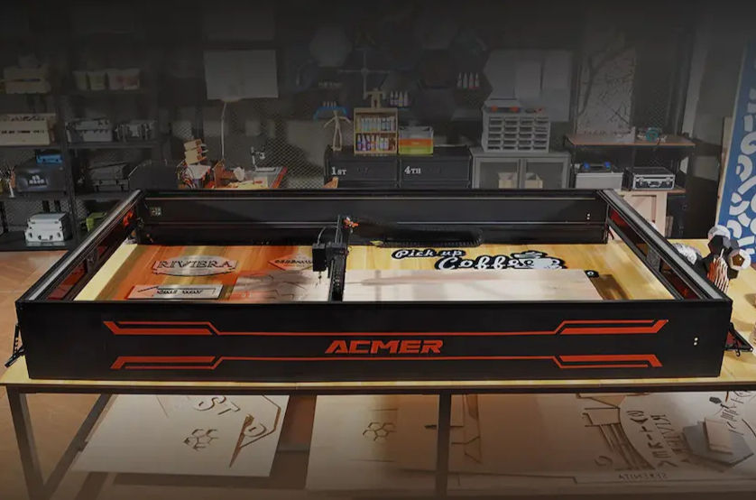 Maker standing beside the ACMER X1 laser engraver in a studio workshop showing the large-format enclosed bed and interior lighting