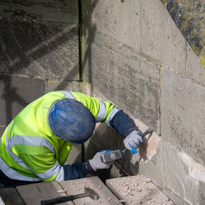Construction worker chiseling stone wall